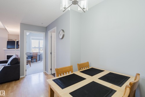 Dining area featuring wood-finish flooring, a contemporary ceiling light fixture, and light gray wall paint - 508 11103 84 Avenue, Edmonton, AB - Indoor