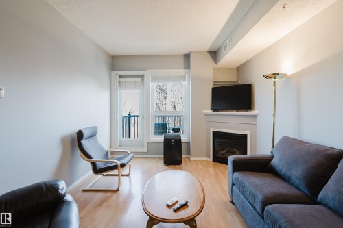 Living area with wood-finish flooring and light gray painted walls - 508 11103 84 Avenue, Edmonton, AB - Indoor Photo Showing Living Room With Fireplace