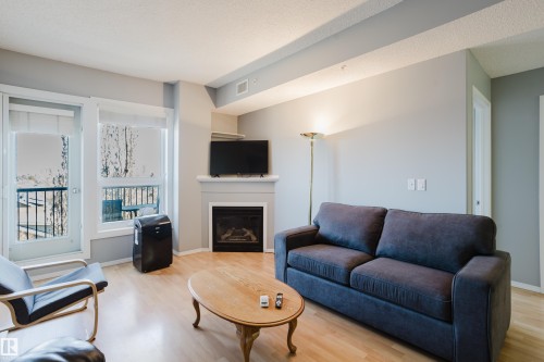 Living space featuring light wood-finish flooring and a white trim baseboard - 508 11103 84 Avenue, Edmonton, AB - Indoor Photo Showing Living Room With Fireplace