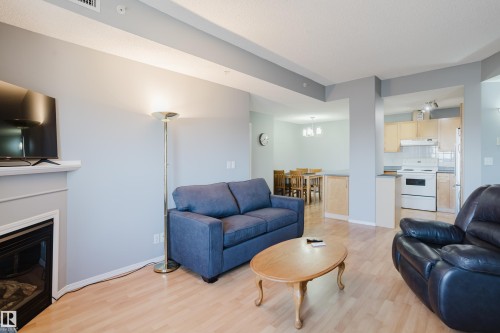 Open-concept living area featuring light wood-finish flooring - 508 11103 84 Avenue, Edmonton, AB - Indoor Photo Showing Living Room With Fireplace