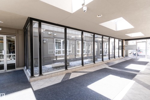 Entry corridor featuring a glass wall with black framing, skylights, tiled flooring, and dual entrance doors - 508 11103 84 Avenue, Edmonton, AB - Indoor Photo Showing Other Room