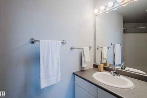 Bathroom vanity featuring an integrated oval sink, dark countertop, and chrome faucet - 508 11103 84 Avenue, Edmonton, AB - Indoor Photo Showing Bathroom