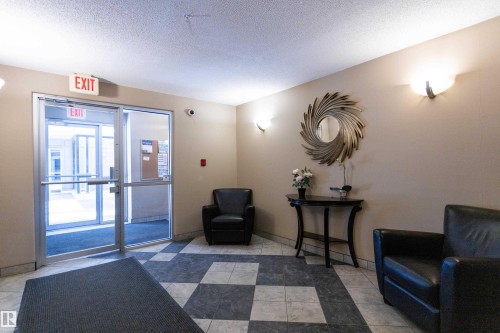 Lobby area featuring checkered tile flooring, neutral wall tones, and sconce lighting - 508 11103 84 Avenue, Edmonton, AB - Indoor Photo Showing Other Room