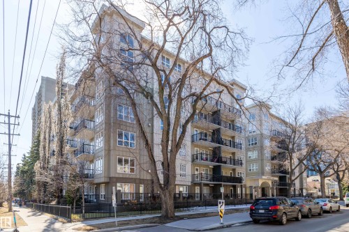 Multi-story residential building featuring a stone and siding exterior, multiple private balconies with black railings, and a prominent front entrance with a portico - 508 11103 84 Avenue, Edmonton, AB - Outdoor With Facade