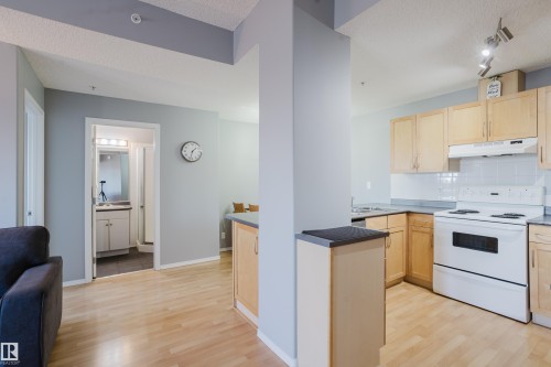 Open-concept kitchen featuring light wood cabinetry, white appliances, and light wood-finish flooring - 508 11103 84 Avenue, Edmonton, AB - Indoor Photo Showing Kitchen