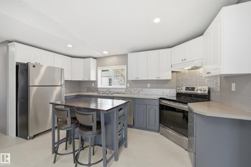 Kitchen featuring a central island, stainless steel appliances, white upper cabinetry, and gray lower cabinetry - 106 Springfield Crescent, Spruce Grove, AB - Indoor Photo Showing Kitchen