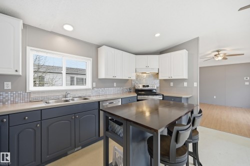 Kitchen featuring two-tone cabinetry with white upper and dark lower units, stainless steel appliances, a square tile backsplash, and recessed lighting - 106 Springfield Crescent, Spruce Grove, AB - Indoor Photo Showing Kitchen With Double Sink