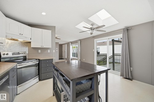 Kitchen featuring stainless steel appliances, a mosaic tile backsplash, and a central island with open shelving - 106 Springfield Crescent, Spruce Grove, AB - Indoor Photo Showing Kitchen