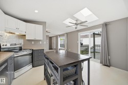 Kitchen featuring stainless steel appliances, a mosaic tile backsplash, and a central island with open shelving - 