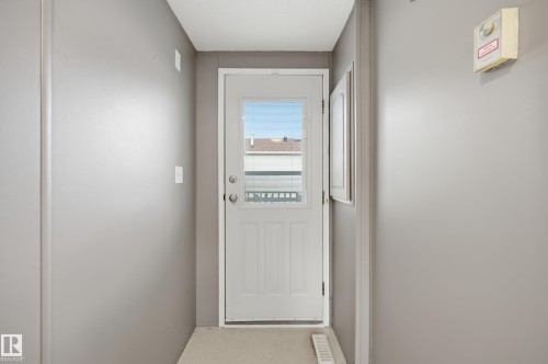 Entryway featuring a white paneled door with a rectangular window, light neutral wall paint, and a built-in wall vent - 106 Springfield Crescent, Spruce Grove, AB - Indoor Photo Showing Other Room