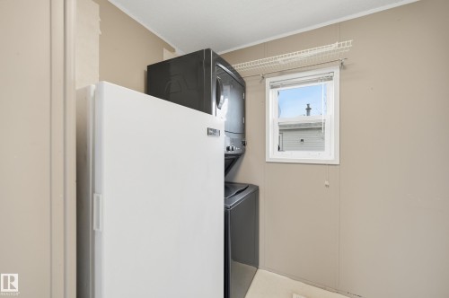 Laundry area featuring a side-by-side washer and dryer, a window with white trim, and a wall-mounted wire shelf - 106 Springfield Crescent, Spruce Grove, AB - Indoor