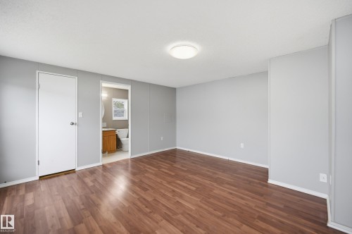 Spacious interior featuring wood-finish flooring, light gray walls, and a contemporary ceiling light fixture - 106 Springfield Crescent, Spruce Grove, AB - Indoor Photo Showing Other Room