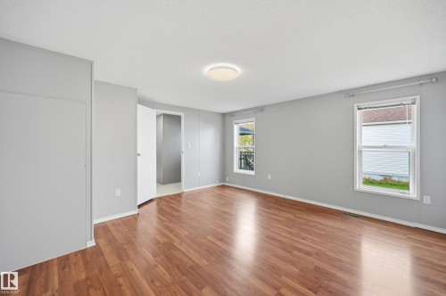 Spacious room with wood-finish flooring, two windows, and a flush-mount ceiling light fixture - 106 Springfield Crescent, Spruce Grove, AB - Indoor Photo Showing Other Room