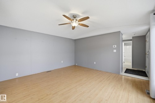 Spacious room with wood-finish flooring, light gray walls, and a ceiling fan with integrated lighting - 106 Springfield Crescent, Spruce Grove, AB - Indoor Photo Showing Other Room