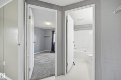 Interior hallway featuring light gray walls, white trim, and a white interior door - 