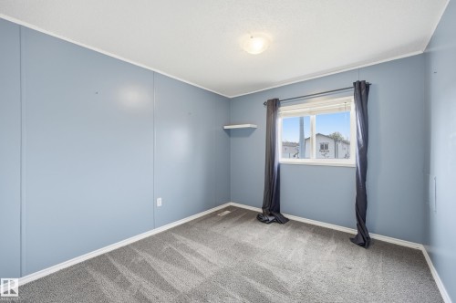 Carpeted room featuring light blue panel walls, white trim, and a window with horizontal blinds - 106 Springfield Crescent, Spruce Grove, AB - Indoor Photo Showing Other Room