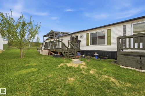 Expansive grassy yard featuring a young tree and two elevated outdoor decks - 106 Springfield Crescent, Spruce Grove, AB - Outdoor