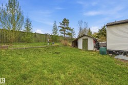 Expansive green lawn with a white storage shed featuring a green door - 