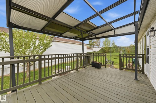Expansive outdoor deck featuring a translucent covered patio structure, wood-finish flooring, and perimeter railing - 106 Springfield Crescent, Spruce Grove, AB - Outdoor With Deck Patio Veranda With Exterior