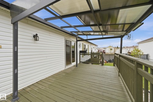 Expansive outdoor deck featuring a transparent overhead covering, wood-finish decking, and coordinating wood-finish railings - 106 Springfield Crescent, Spruce Grove, AB - Outdoor With Deck Patio Veranda With Exterior