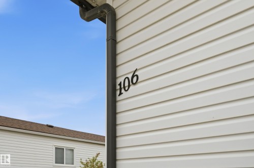 White horizontal siding exterior with dark house numbers and a matching dark downspout - 106 Springfield Crescent, Spruce Grove, AB - Outdoor