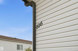 White horizontal siding exterior with dark house numbers and a matching dark downspout - 