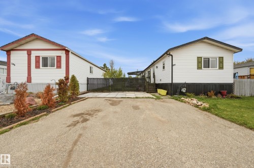 Front exterior featuring white siding with contrasting trim, a gabled roofline, and a paved driveway - 106 Springfield Crescent, Spruce Grove, AB - Outdoor