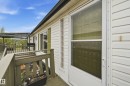 White siding exterior featuring a covered deck, glass block window, sliding glass door, and green painted wooden railings - 106 Springfield Crescent, Spruce Grove, AB  - Outdoor With Deck Patio Veranda With Exterior 