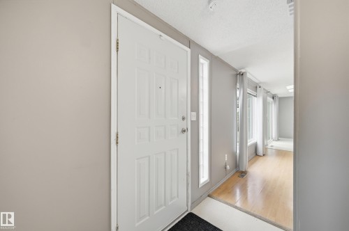 Entryway featuring a paneled door with sidelight windows, light gray wall finishes, and wood-finish flooring - 106 Springfield Crescent, Spruce Grove, AB - Indoor Photo Showing Other Room