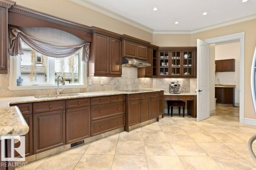 Spacious kitchen featuring warm wood cabinetry, light-toned tiled flooring, and granite countertops - 58 Riverstone Close, Rural Sturgeon County, AB - Indoor Photo Showing Kitchen