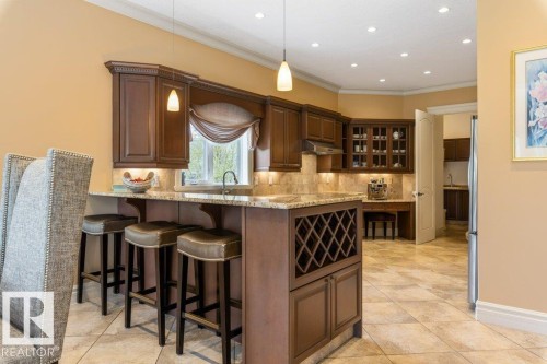 Kitchen featuring wood cabinetry, stone countertops, a built-in wine rack, tile flooring, and recessed lighting - 58 Riverstone Close, Rural Sturgeon County, AB - Indoor Photo Showing Kitchen