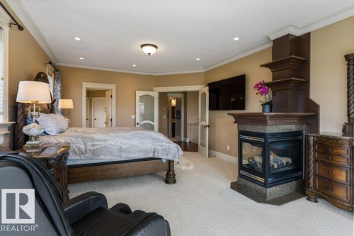 Bedroom featuring an ornate built-in fireplace with a stone hearth, integrated shelving, and recessed lighting - 58 Riverstone Close, Rural Sturgeon County, AB - Indoor Photo Showing Bedroom With Fireplace