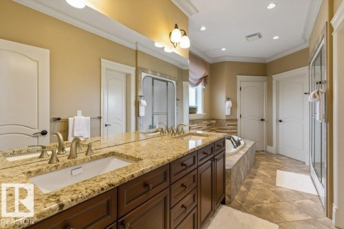 Double vanity with a speckled countertop, undermount sinks, and brushed brass fixtures - 58 Riverstone Close, Rural Sturgeon County, AB - Indoor Photo Showing Bathroom