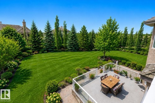 Expansive backyard featuring a manicured lawn, mature trees, and landscaping - 58 Riverstone Close, Rural Sturgeon County, AB - Outdoor