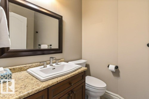 Bathroom vanity featuring a granite countertop, undermount sink, and dark wood cabinetry - 58 Riverstone Close, Rural Sturgeon County, AB - Indoor Photo Showing Bathroom