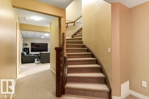 Curved staircase featuring carpeted treads and a dark wood-finish banister - 58 Riverstone Close, Rural Sturgeon County, AB - Indoor Photo Showing Other Room