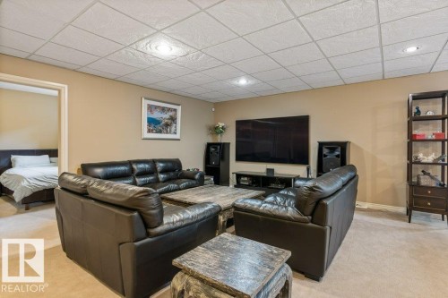 Carpeted recreation room featuring an acoustic tile ceiling with recessed lighting and neutral wall paint - 58 Riverstone Close, Rural Sturgeon County, AB - Indoor