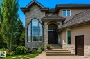 Stone and stucco exterior featuring an arched entrance, multi-pane arched window, dark wood double entry doors, textured roof, and landscaped garden beds - 58 Riverstone Close, Rural Sturgeon County, AB  - Outdoor With Facade 