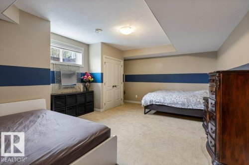Carpeted room with a double-paned window, neutral wall paint with a contrasting accent stripe, and a white interior door - 58 Riverstone Close, Rural Sturgeon County, AB - Indoor Photo Showing Bedroom