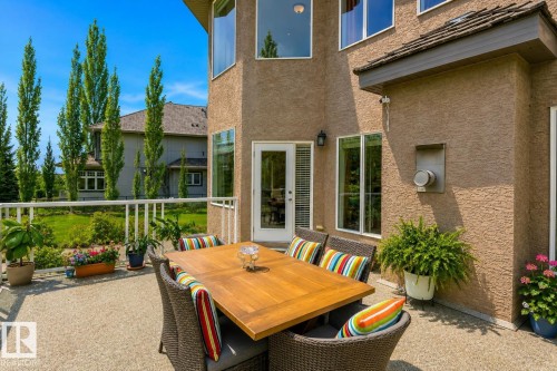 Exterior stucco finish with a ground-level patio featuring a white railing and multiple large windows - 58 Riverstone Close, Rural Sturgeon County, AB - Outdoor With Deck Patio Veranda With Exterior