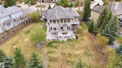 Spacious rear yard featuring a large stone patio, mature trees, and landscaping - 58 Riverstone Close, Rural Sturgeon County, AB - Outdoor
