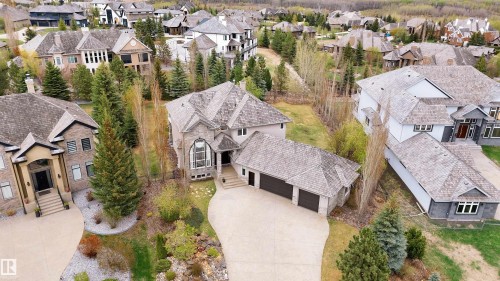 Expansive property featuring a stone and stucco exterior, multiple gabled roofs, an attached multi-car garage, and a large paved driveway - 58 Riverstone Close, Rural Sturgeon County, AB - Outdoor