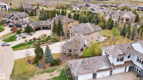 Residential street with multiple properties featuring mature landscaping, paved driveways, and sloped terrain - 58 Riverstone Close, Rural Sturgeon County, AB - Outdoor