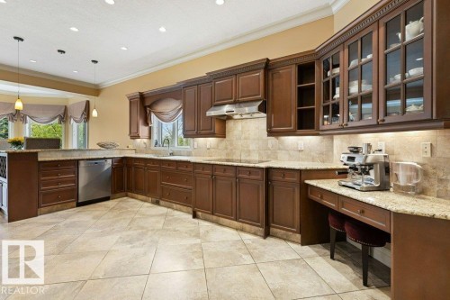 Gourmet kitchen featuring extensive wood cabinetry, granite countertops, and a full tile backsplash - 58 Riverstone Close, Rural Sturgeon County, AB - Indoor Photo Showing Kitchen With Upgraded Kitchen