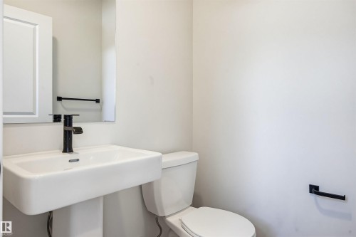Pedestal sink with a matte black faucet, wall-mounted mirror, and white paneled medicine cabinet - 22429 83A Avenue, Edmonton, AB - Indoor Photo Showing Bathroom