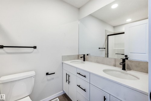 Dual vanity with white cabinetry, matte black hardware, and an expansive mirror - 22429 83A Avenue, Edmonton, AB - Indoor Photo Showing Bathroom