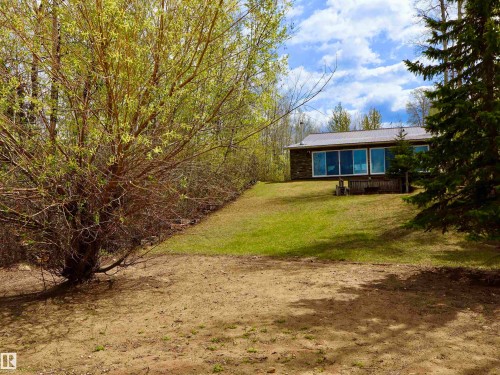 Wood-sided home featuring a metal roof, expansive windows, and an elevated deck - #26 5508 Twp Rd 593A, Rural Barrhead County, AB - Outdoor