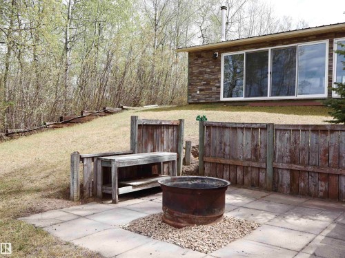 Patio area featuring large format pavers, a central fire pit with gravel surround, and a built-in wooden bench - #26 5508 Twp Rd 593A, Rural Barrhead County, AB - Outdoor