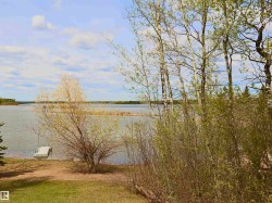 Waterfront property featuring a private dock and mature trees - 