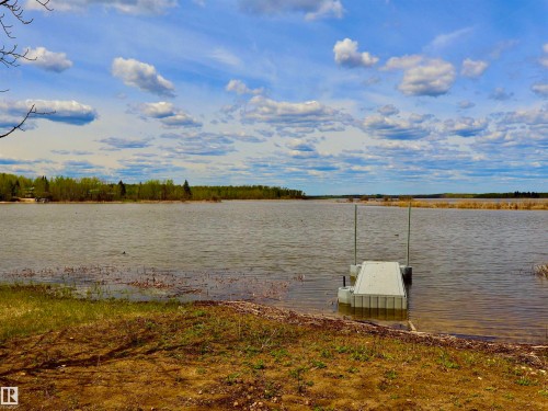 Waterfront property featuring a floating dock, natural shoreline, and distant tree line - #26 5508 Twp Rd 593A, Rural Barrhead County, AB - Outdoor With Body Of Water With View